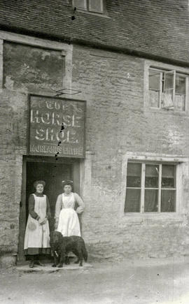 Horse Shoe, 1910. Two ladies and a dog in the doorway